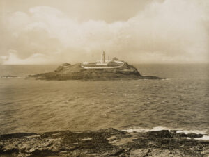 遥望小岛上的灯塔，四周是低矮的石墙。